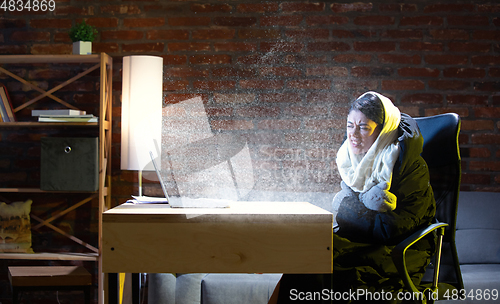 Image of Young woman in oversized black puffy jacket meeting winter on virtual video call