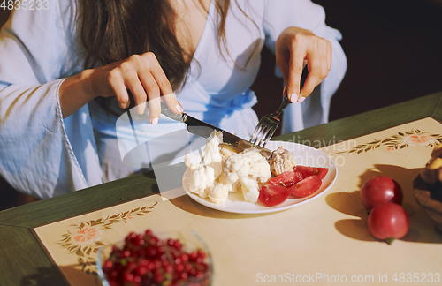 Image of Vegetarian woman sitting at the table and eating healthy food