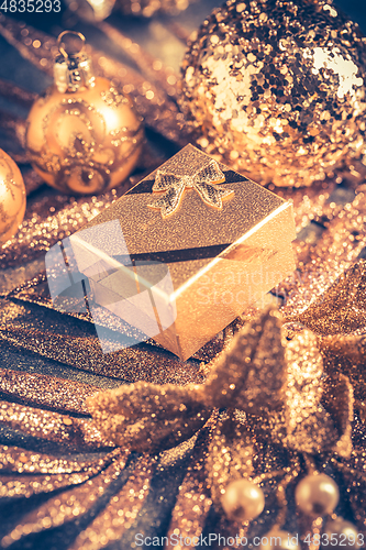 Image of Christmas ornaments with small present in golden tones