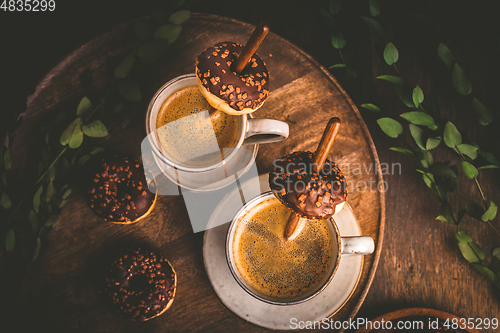 Image of Two cups of Caffe Americano with small chocolate donuts