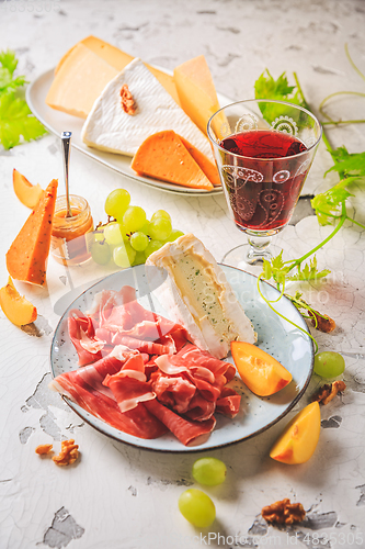 Image of Ham and cheese platter with grapes and red wine