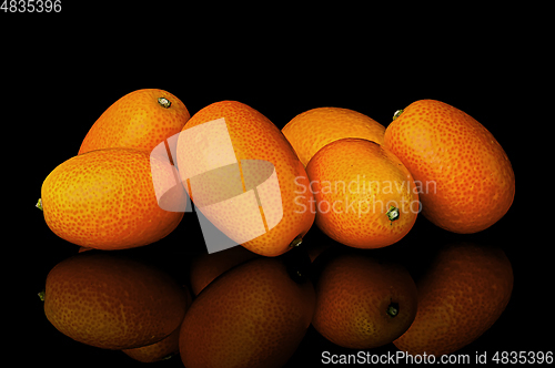 Image of Heap of ripe kumquats on black background