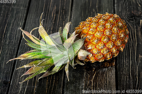 Image of Ripe pineapple lies on a wooden table