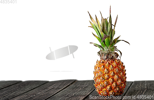 Image of Pineapple stands on wooden boards isolated on white