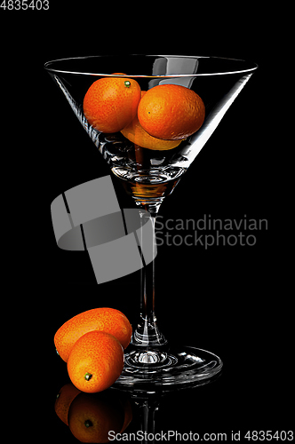 Image of Ripe kumquat in martini glass with reflection