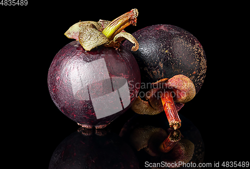 Image of Two ripe mangosteen one after another on a black