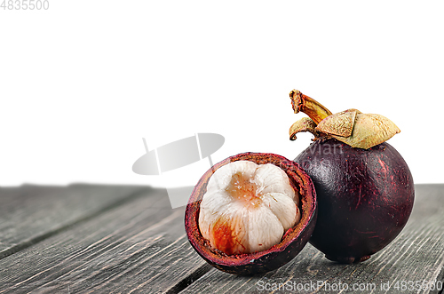 Image of Whole and opened mangosteen on table isolated on white