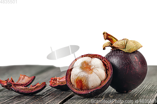 Image of Whole and opened mangosteen with shells on table