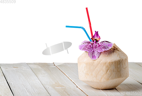 Image of Young coconut with orchid flower on wooden table