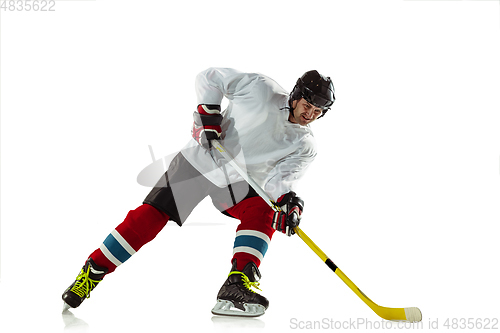 Image of Young male hockey player with the stick on ice court and white background