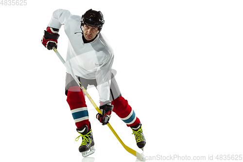 Image of Young male hockey player with the stick on ice court and white background