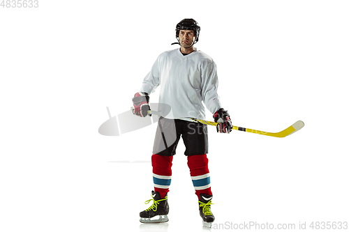 Image of Young male hockey player with the stick on ice court and white background