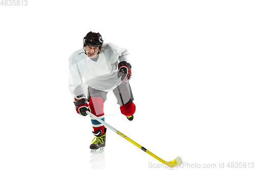 Image of Young male hockey player with the stick on ice court and white background