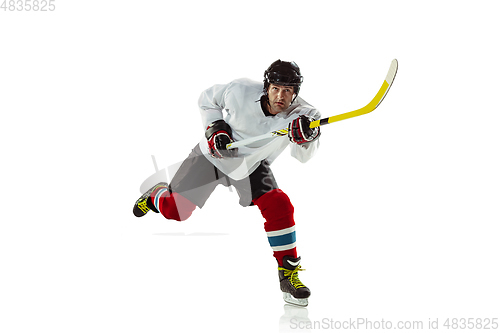 Image of Young male hockey player with the stick on ice court and white background