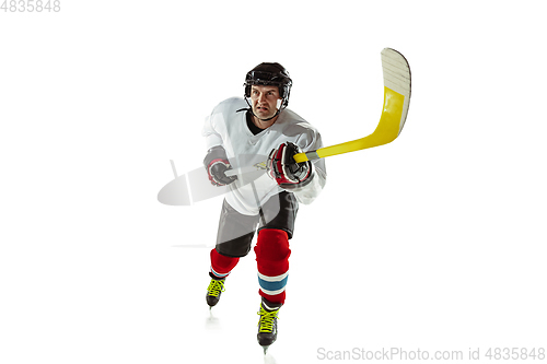 Image of Young male hockey player with the stick on ice court and white background