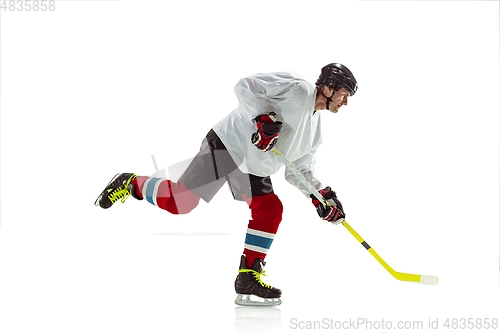 Image of Young male hockey player with the stick on ice court and white background