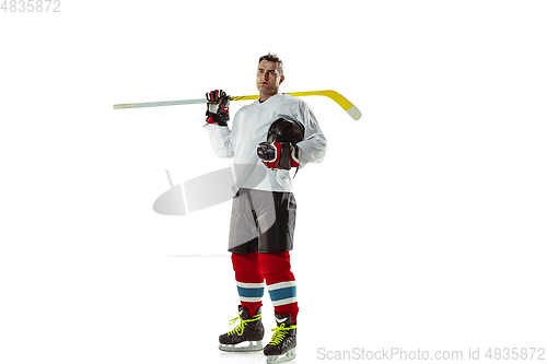 Image of Young male hockey player with the stick on ice court and white background