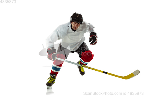 Image of Young male hockey player with the stick on ice court and white background