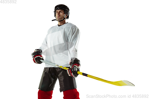 Image of Young male hockey player with the stick on ice court and white background