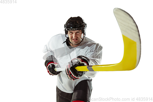 Image of Young male hockey player with the stick on ice court and white background