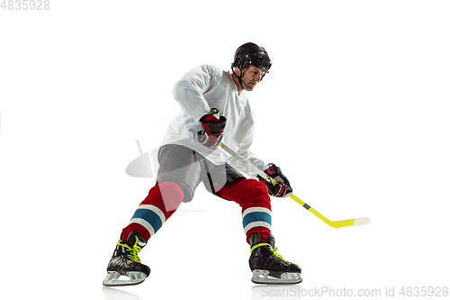 Image of Young male hockey player with the stick on ice court and white background