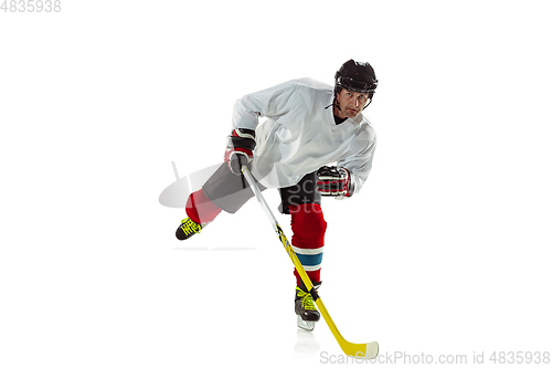 Image of Young male hockey player with the stick on ice court and white background