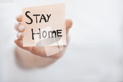 Image of Hand holding sticky note with Stay Home text