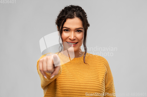 Image of smiling young woman pointing finger to camera