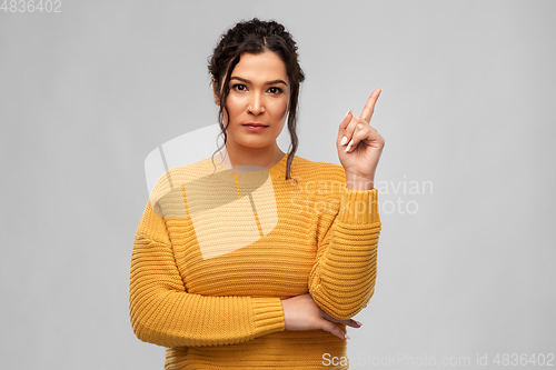 Image of serious young woman pointing finger up