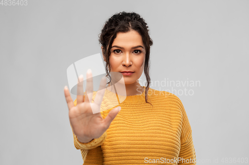 Image of woman showing stop gesture over grey background