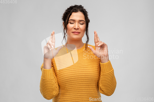 Image of woman with pierced nose holding fingers crossed