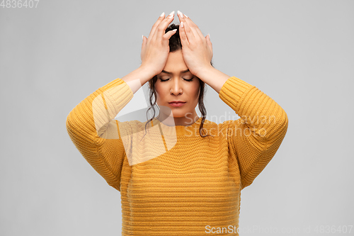 Image of stressed young woman holding to her head