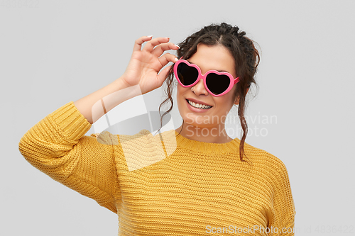 Image of smiling young woman in heart-shaped sunglasses