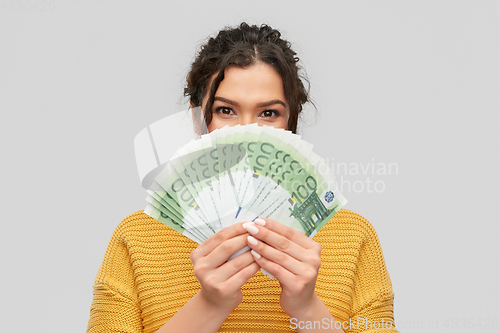 Image of young woman covering her face with euro money