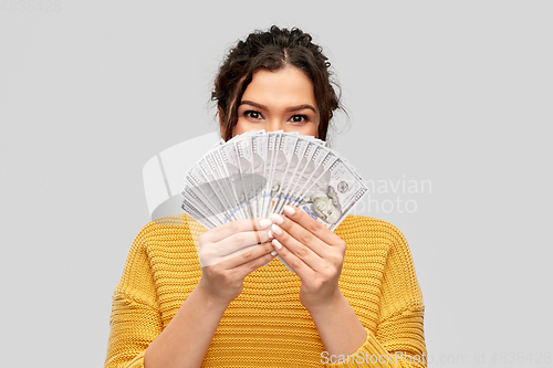 Image of young woman covering her face with dollar money