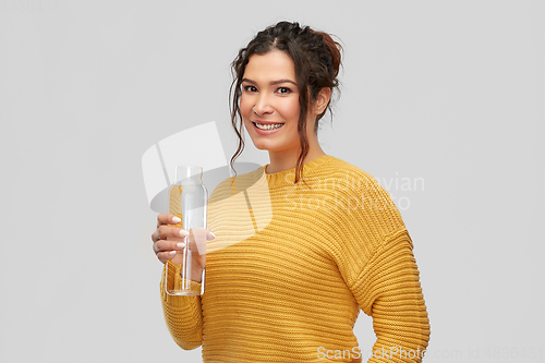 Image of smiling young woman with water in glass bottle