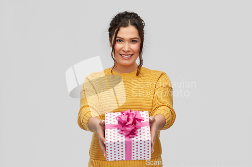Image of smiling young woman holding gift box