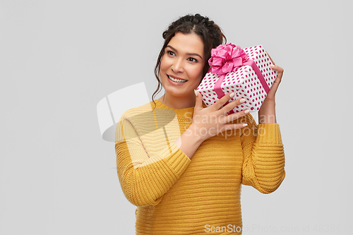 Image of smiling young woman holding gift box