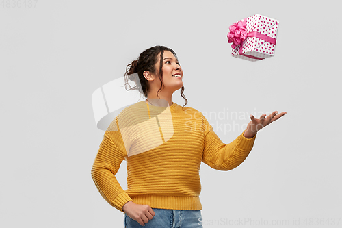 Image of smiling young woman throwing gift box