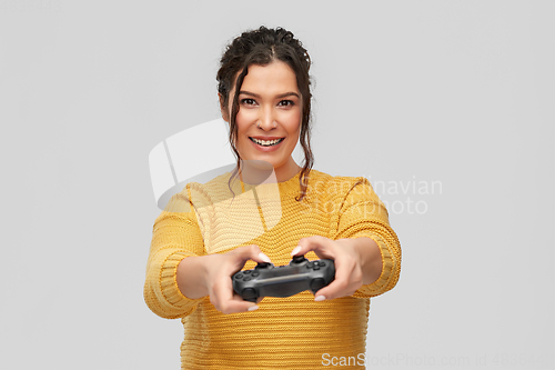 Image of happy young woman with gamepad playing video game