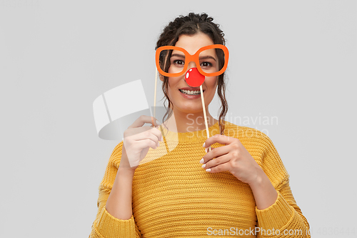 Image of happy young woman with red clown nose and glasses
