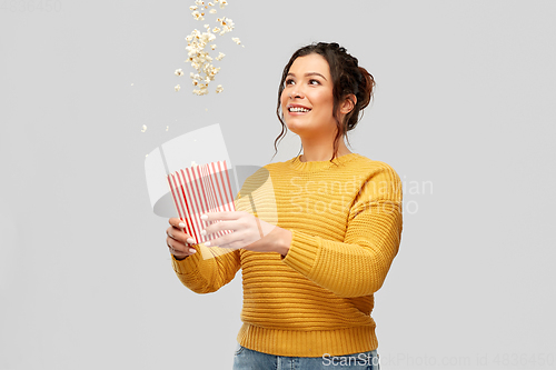 Image of happy smiling young woman playing with popcorn