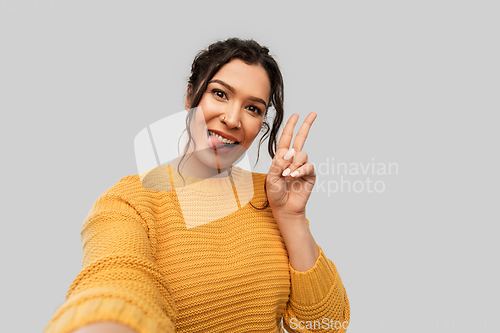 Image of woman with pierced nose taking selfie shows peace