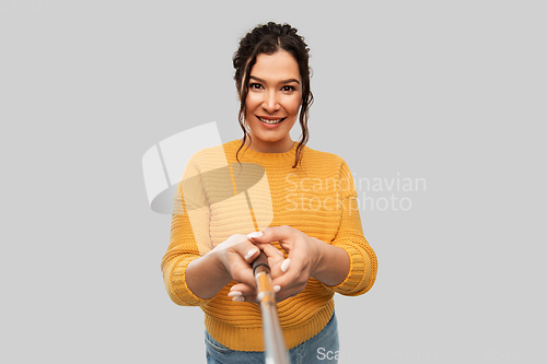 Image of smiling woman taking picture with selfie stick