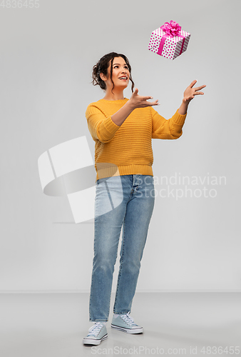 Image of smiling young woman throwing gift box