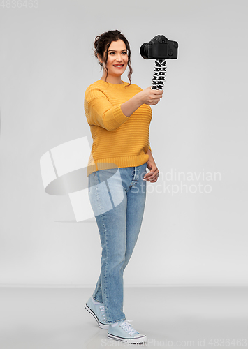 Image of smiling woman blogger with camera recording video