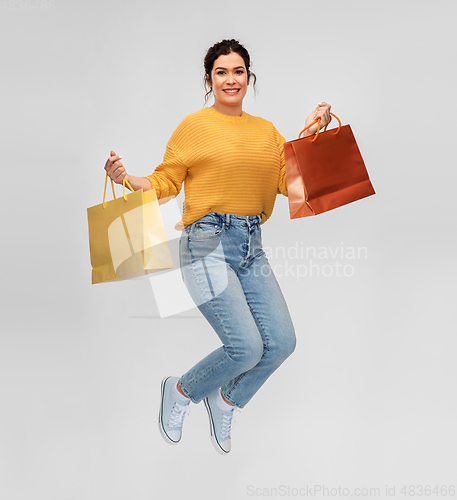 Image of happy young woman jumping with shopping bags