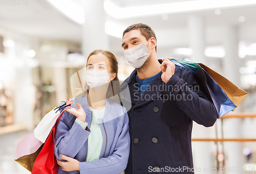 Image of couple in medical masks with shopping bags in mall