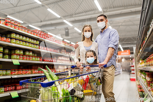 Image of family with shopping cart in masks at supermarket