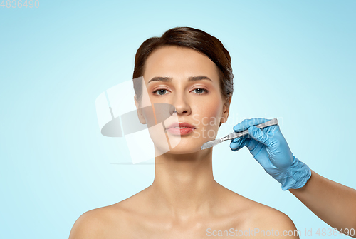 Image of beautiful young woman and hand with scalpel